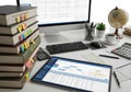 Modern workspace featuring a stack of books, tablet with calendar, keyboard, globe, and coffee mug on a white desk Royalty Free Stock Photo