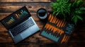top view of a laptop with colorful bar charts on screen and printed graphs next to a cup of coffee on wooden table with plant Royalty Free Stock Photo