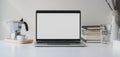 Modern workspace with open blank screen laptop computer with coffee cup and office supplies on white wooden table and white wall Royalty Free Stock Photo