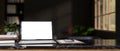 A modern workspace with a white-screen laptop mockup on a black marble table in a modern black room Royalty Free Stock Photo