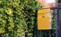 Modern yellow mail box on black fence with beautiful yellows background Royalty Free Stock Photo