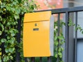 Modern yellow mail box on black fence with beautiful yellows background Royalty Free Stock Photo