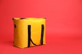 Modern yellow thermo bag on red background. Space for text Royalty Free Stock Photo