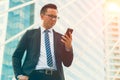 Modern young businessman wear black suit hand holding smartphone. Professional business man standing outside office Royalty Free Stock Photo