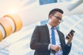 Modern young businessman wear black suit hand holding smartphone. Professional business man standing outside office Royalty Free Stock Photo