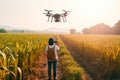 Modern young farmer using flying drone to inspect the rural farm.