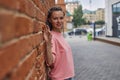 a modern young girl with braids stands leaning against a brick wall Royalty Free Stock Photo