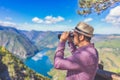 Fashionable man using binoculars and looking at beautiful nature with mountains and canyon Royalty Free Stock Photo