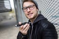 Modern young man talking on the phone with hands free in the street. Royalty Free Stock Photo