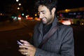 Modern young man using his mobile phone in the street at night. Royalty Free Stock Photo