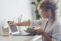 Modern young pretty adult lady working at home in alternative office work place with laptop computer and notebook taking notes. Royalty Free Stock Photo