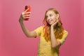 Modern young smiling happy girl doing selfie shot on mobile phone for social network content on pink studio background Royalty Free Stock Photo