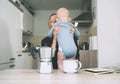 Modern tired mother and little child after sleepless night. Exhausted woman with baby is sitting with coffee in kitchen. Life of Royalty Free Stock Photo