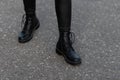 Modern young woman in black stylish leggings in fashionable leather boots stands on the road in the city. Trendy collection of Royalty Free Stock Photo