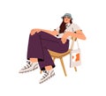 Modern young woman sitting in chair, posing in trendy outfit. Happy stylish girl in fashion casual clothes, wearing Royalty Free Stock Photo