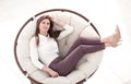 Modern young woman sitting in comfortable round chair