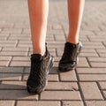 Modern young woman with slender beautiful legs in fashionable black sneakers walks down the street. Stylish sporty women`s shoes. Royalty Free Stock Photo