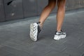 Modern young woman with slender beautiful legs in fashionable silver sneakers walks on the street. Stylish women`s shoes. Summer Royalty Free Stock Photo