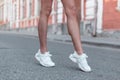 Modern young woman with slender beautiful legs in fashionable white sneakers walks down the street. Stylish sporty women`s shoes. Royalty Free Stock Photo