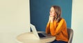 Modern young woman working with laptop sitting at the desk in the room at home and pensive looking out the window Royalty Free Stock Photo