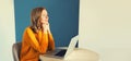 Modern young woman working with laptop sitting at the desk in the room at home and pensive looking out the window Royalty Free Stock Photo