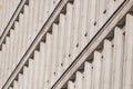 A modernist facade with repeating vertical concrete elements, creating rhythmic patterns and dynamic diagonal shadows