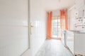 Modest and old kitchen with little furniture with access to a terrace with orange curtains