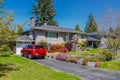 Modest residential house with red car parked on driveway in front. Family house with blossoming flowers on the yard Royalty Free Stock Photo