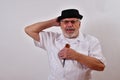 Modest senior man smiling and hanging on to his hat