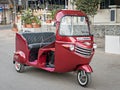 Modified and decorated red colored three wheeler autorikshaw on the street