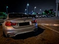 Modified gray BMW M4 Coupe parked in an outdoor parking at night