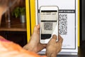 Modified inactive QR Code used. Person scanning QR code with smartphone to register details before enter outlet to comply with