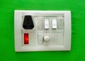 A Modular white electricity switch and socket board isolated on green wall Royalty Free Stock Photo