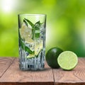 Mohito cocktail on wooden table against green background