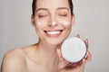 Close up beauty portrait of a laughing beautiful half naked woman with eyes closed holds in hand face cream Royalty Free Stock Photo