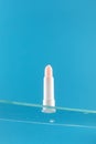 Moisturizing pink hygienic lipstick on a glass shelf on a blue background.