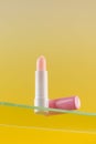 Moisturizing pink hygienic lipstick on a glass shelf on a yellow background.