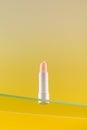 Moisturizing pink hygienic lipstick on a glass shelf on a yellow background.