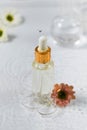 Moisturizing serum for the skin stands in water with flowers on a white background. Royalty Free Stock Photo