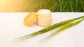 Moisturizing skin cream with green spikelet on a white stand in the rays of sunlight, body care cosmetics, beauty