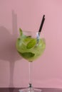 Mojito alcohol cocktail with plastic straw, tropical beverage with ice, mint and lime on pink background, copy space. Royalty Free Stock Photo