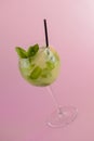 Mojito alcohol cocktail with plastic straw, tropical beverage with ice, mint and lime on pink background, copy space. Royalty Free Stock Photo