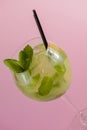 Mojito alcohol cocktail with plastic straw, tropical beverage with ice, mint and lime on pink background, copy space. Royalty Free Stock Photo