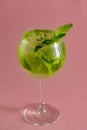Mojito alcohol cocktail, tropical beverage with ice, mint and lime on pastel pink background with copy space. Royalty Free Stock Photo