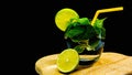 Mojito alcoholic cocktail on a black background. Mint drink in a glass with a straw and lime. Summer refreshing drink Royalty Free Stock Photo