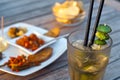 Mojito cocktail with snacks on wooden table