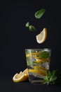 Mojito with falling mint and lemon on black