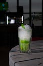 Mojito Long Drink decorated with lime and mint with crushed ice. In a glass goblet collins. On a gray wooden background. Close-up