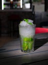 Mojito Long Drink decorated with lime and mint with crushed ice. In a glass goblet collins. On a gray wooden background. Close-up