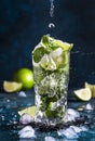 Mojito with splash and drops. Cocktail or mocktail with lime, mint, and ice in glass on blue background. Summer cold alcoholic non Royalty Free Stock Photo